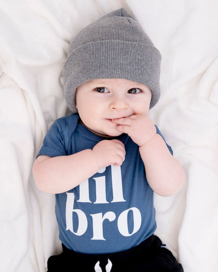 Baby wearing blue 'lil bro' bodysuit and gray knit hat