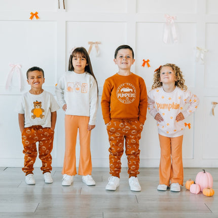 four kids wearing matching outfits with pumpkins.