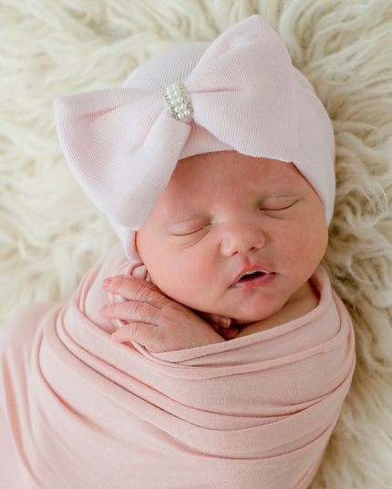 Baby wearing a pink hat with pink jeweled bow