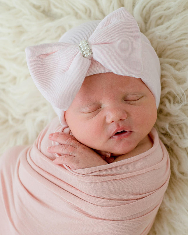 Baby wearing a pink hat with pink jeweled bow