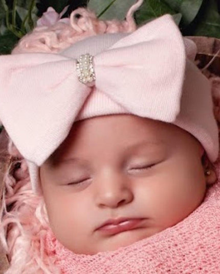Baby wearing a pink hat with pink jeweled bow
