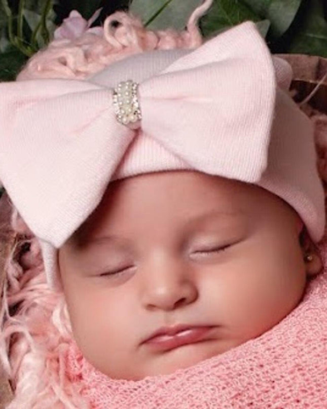 Baby wearing a pink hat with pink jeweled bow