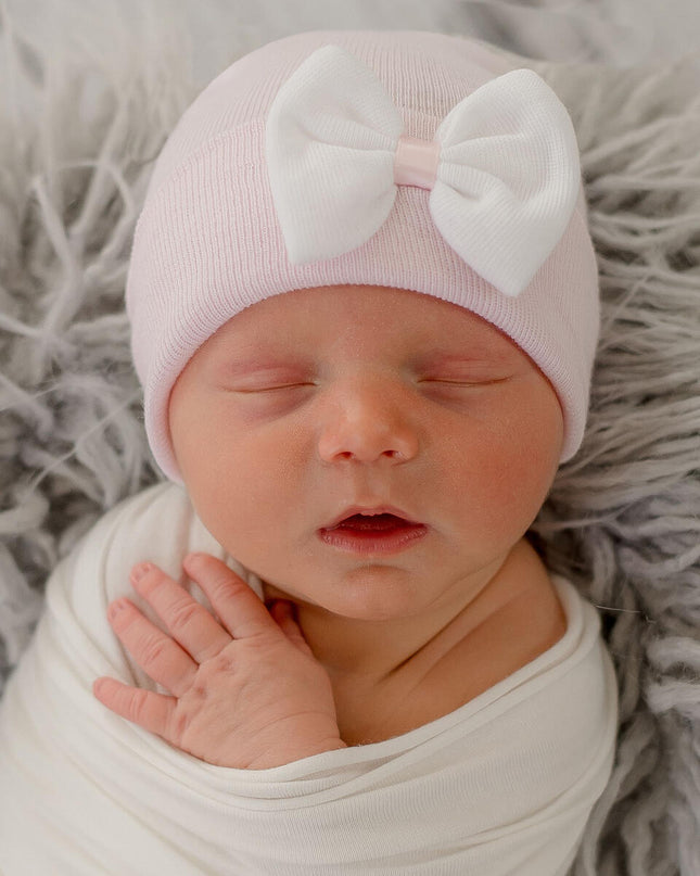 Baby wearing pink hospital hat with white bow accent