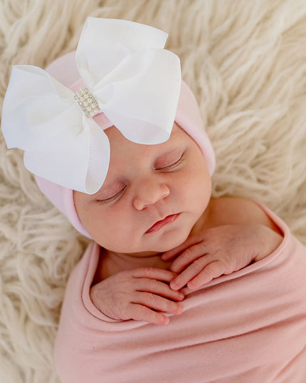 Baby wearing a pink hospital hat with an oversized white bow and decorative center