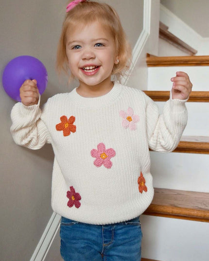 Girl wearing cream sweater with crochet flowers and jeans