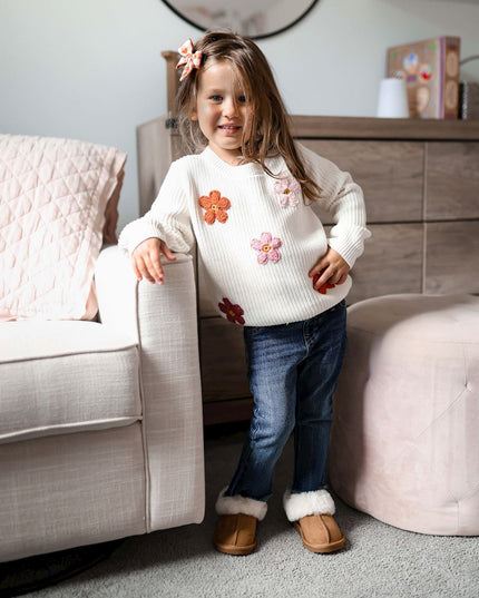 Girl wearing cream sweater with crochet flowers and jeans