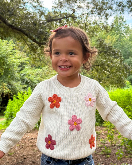 Girl wearing cream sweater with crochet flowers and jeans