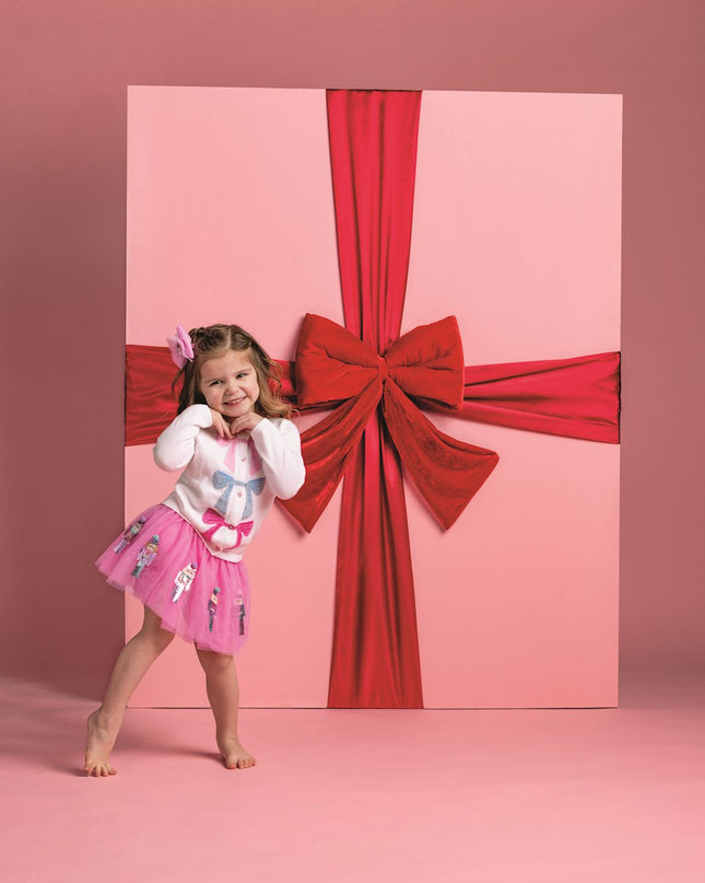 Young girl wearing colorful bow cardigan and tutu skirt
