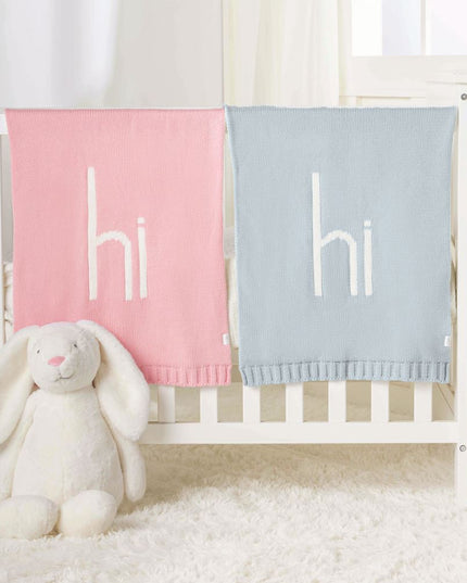 Crib with pink and blue 'hi' blankets and a plush bunny