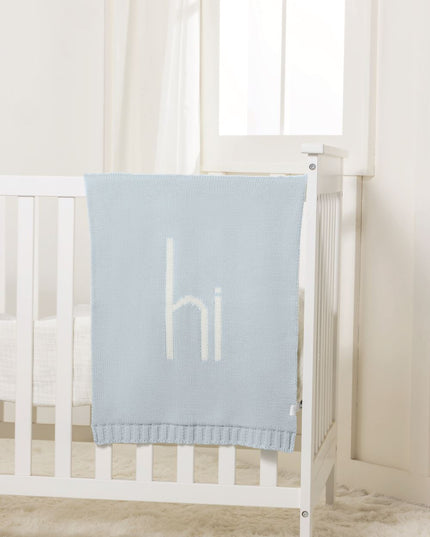 crib with blue 'hi' blanket