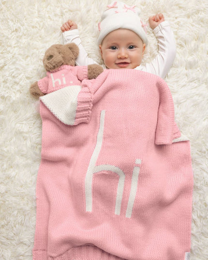 Baby with pink "hi" blanket and teddy hear