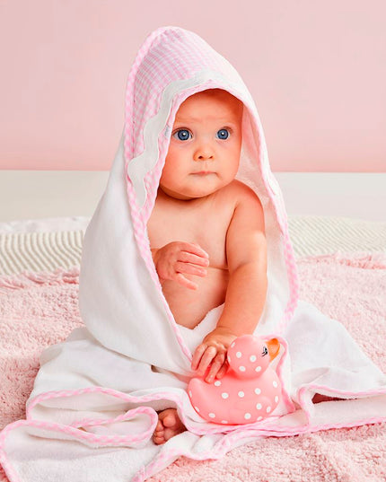 A baby wrapped in a pink and white hooded towel 