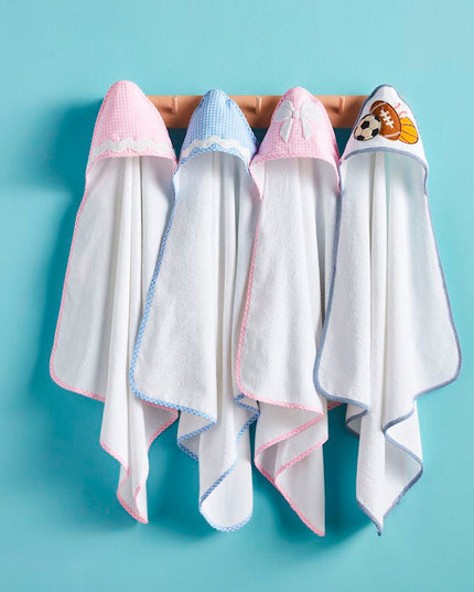 Four white hooded baby towels hanging from a wooden rack 