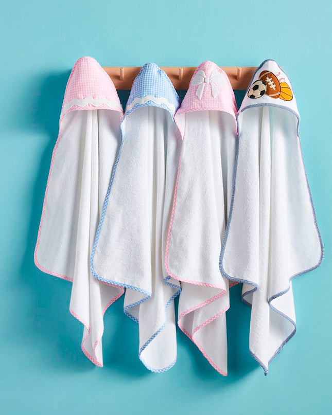 Four white hooded baby towels hanging from a wooden rack 