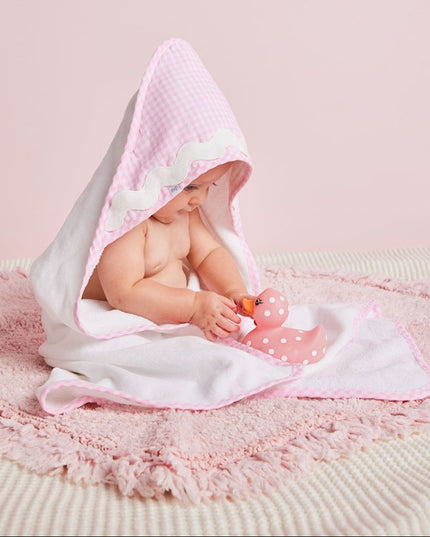 A baby wrapped in a pink and white hooded towel 