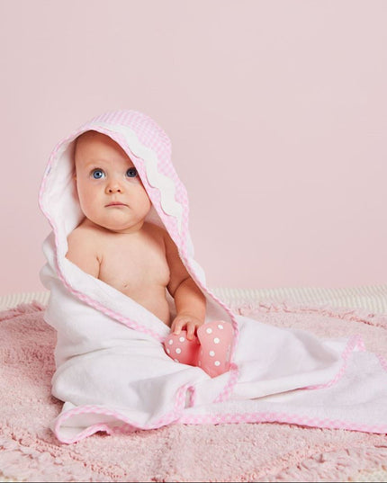 A baby wrapped in a pink and white hooded towel 