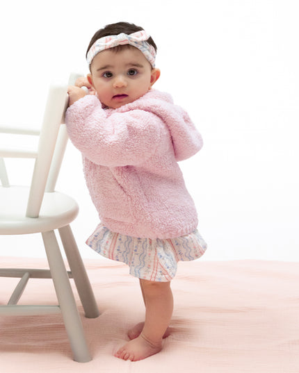 A toddler standing wearing a pink chenille hooded jacket