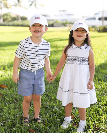Two kids holding hands wearing American flag hats
