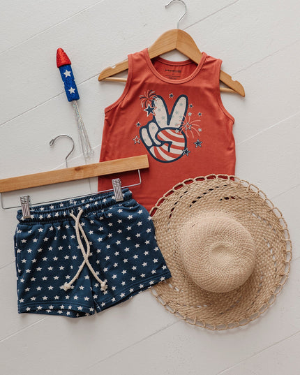 Children's tank top with peace sign design, navy shorts with white stars and straw hat flat lay