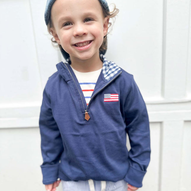 Boy wearing navy blue quarter zip sweatshirt with American flag