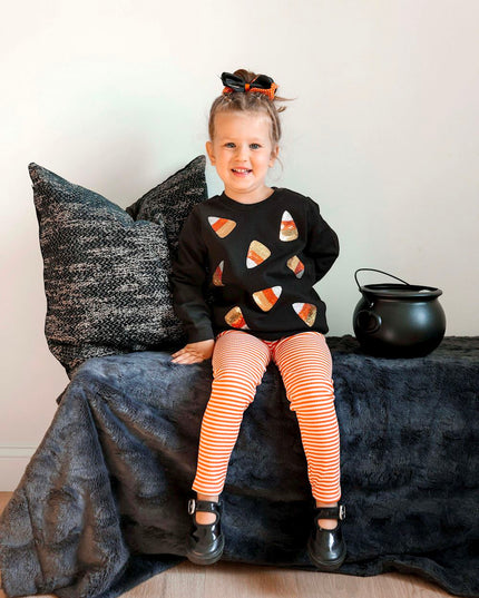 Girl wearing Black sweatshirt with sequin candy corn patches and orange striped leggings 