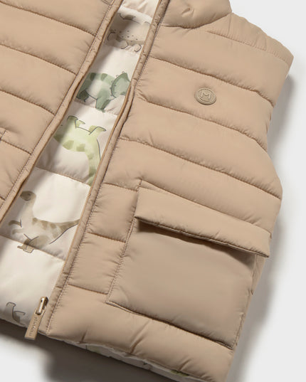 Beige puffer vest with a dinosaur pattern on the inside