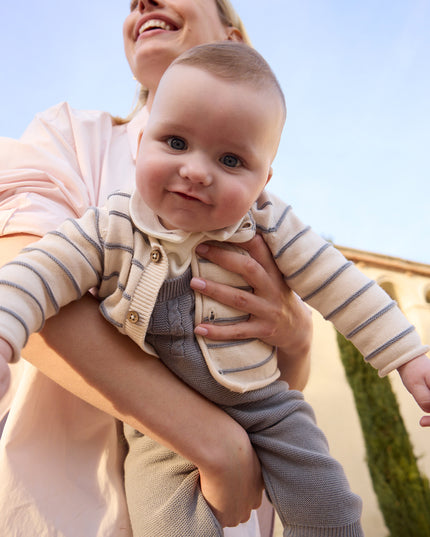 Baby wearing knit dungarees and cardigan set
