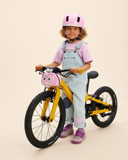 Child with a yellow bicycle and pink Unicorn Handlebar Bag