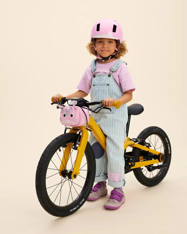 Child with a yellow bicycle and pink Unicorn Handlebar Bag