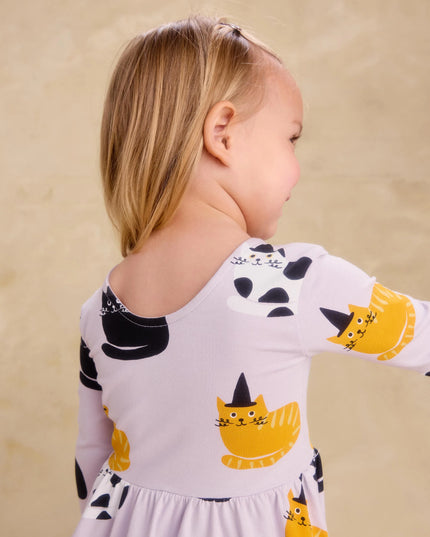 Girl wearing purple dress with black, white and gold cats wearing black witch hats