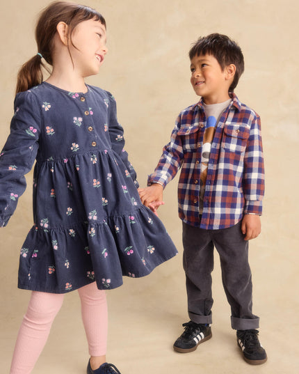 a young girl wearing a deep midnight corduroy shirtdress with floral pattern and pink leggings and a boy wearing a plaid shirt and black jeans