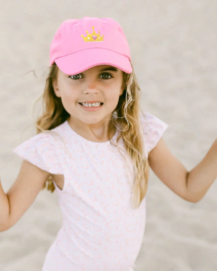 Girl wearing Pink baseball cap with a gold crown 