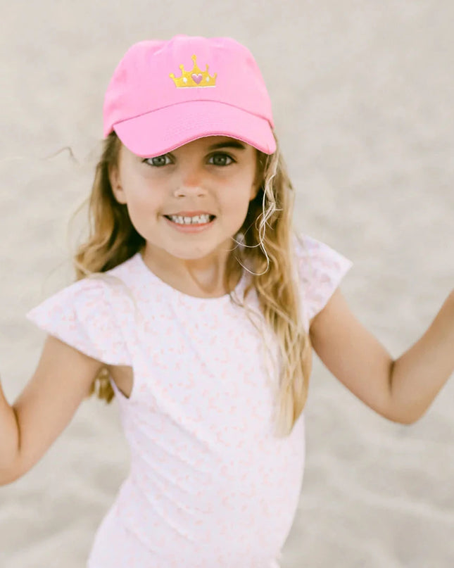 Girl wearing Pink baseball cap with a gold crown 