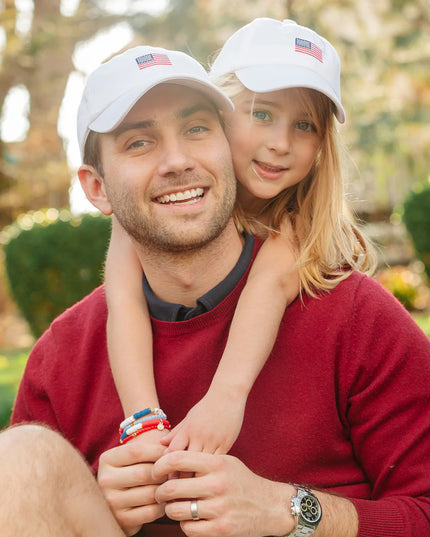 Man and girl wearing matching American flag baseball hats