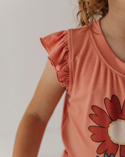 Girl wearing coral ruffle sleeve top with flower design