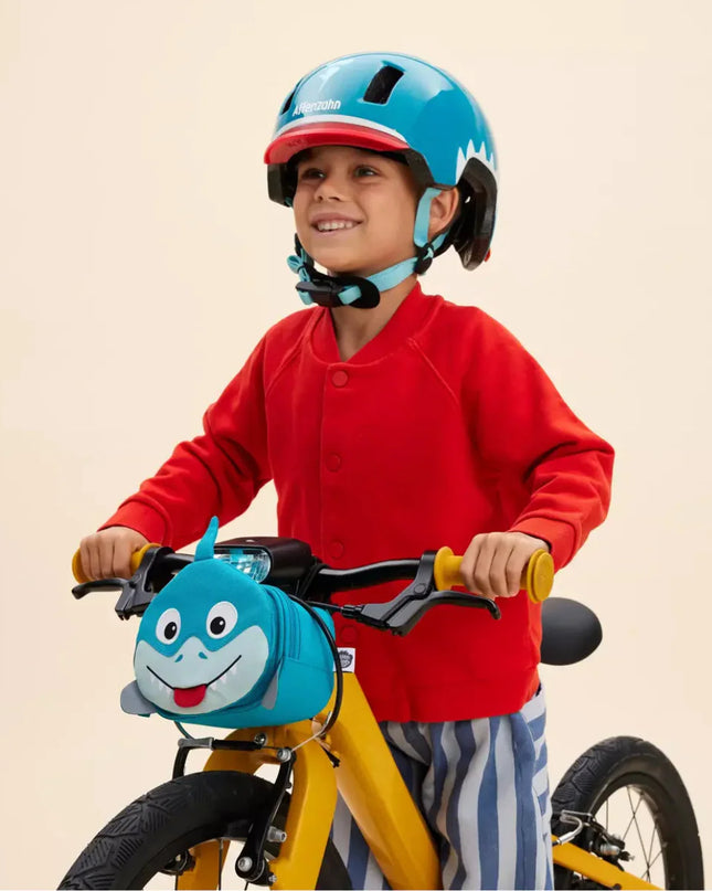 Child  riding a yellow bicycle with a blue shark handlebar bag