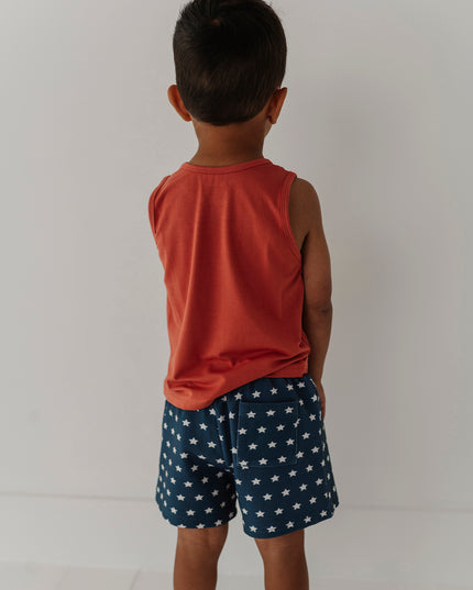 Boy wearing red tank top and blue shorts with white stars
