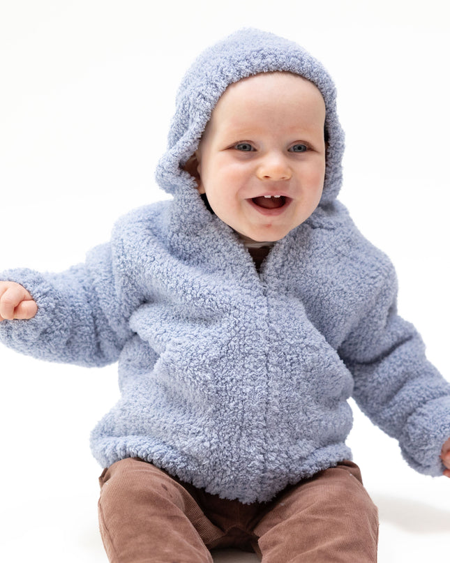 A baby wearing a light blue fuzzy hooded jacket and brown pants