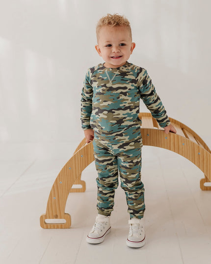 A child wearing a matching camouflage sweatshirt and jogger pants set