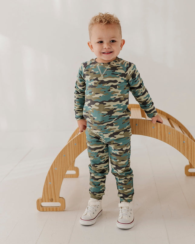 A child wearing a matching camouflage sweatshirt and jogger pants set