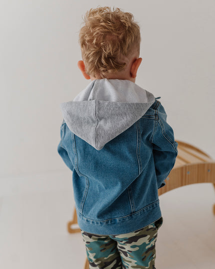 A toddler wearing hooded denim jacket and camouflage pants