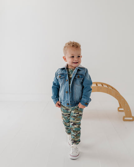 A child wearing a denim jacket and camouflage jogger pants