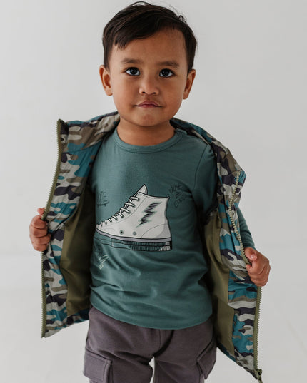 Boy wearing green long sleeve tee with sneaker design and camo jacket 