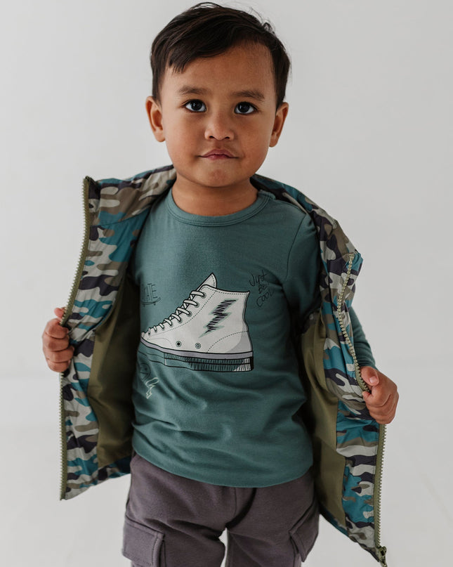 Boy wearing green long sleeve tee with sneaker design and camo jacket 