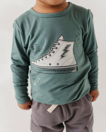 Boy wearing green long sleeve tee with sneaker design and grey pants