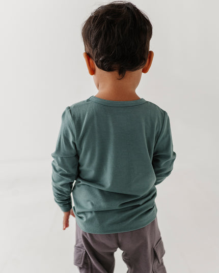Boy wearing green long sleeve tee with sneaker design and grey pants