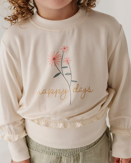 Girl wearing cream color sweatshirt with floral 'happy days' design and green cargo pants