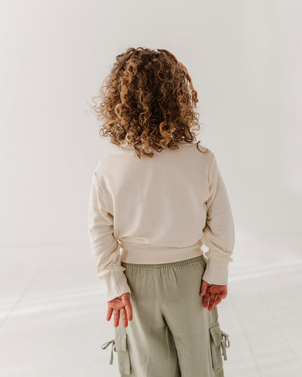 Girl wearing cream color sweatshirt and green cargo pants