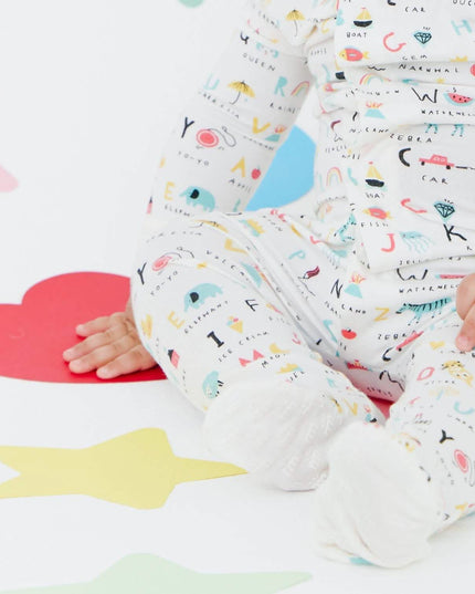 Baby wearing magnetic footie pajamas in ABC's print