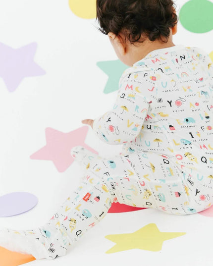 Baby wearing magnetic footie pajamas in ABC's print